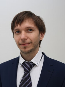 Fedorov im Anzug mit Krawatte, leicht lächelnd, vor hellem Hintergrund.